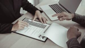 Two professionals reviewing a resume during a meeting, illustrating the evaluation step in answer to how do executive search firms shortlist executives.